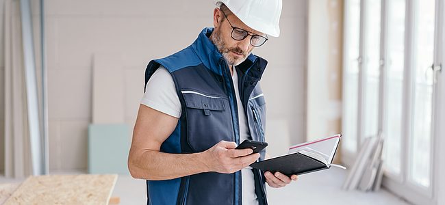 Bild von einem Handwerker mit einem Handy und einem Notizbuch