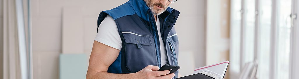 Bild von einem Handwerker mit einem Handy und einem Notizbuch