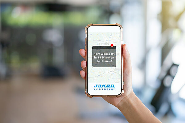 Hand hält Smartphone mit Benachrichtigung über Ankunftszeit