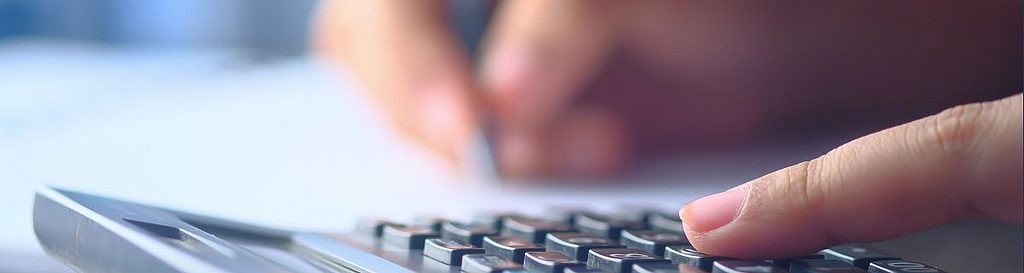 Person berechnet Spesen händisch mit Taschenrechner