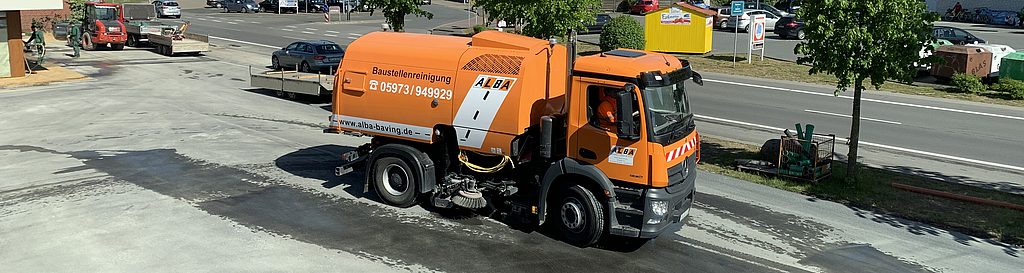 Orangene Kehrmaschine im Einsatz auf einem Parkplatz