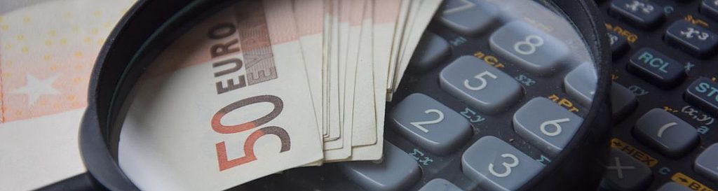 Lupe über 50-Euro-Scheinen und Taschenrechner, Symbol für Kostenanalyse oder Finanzprüfung