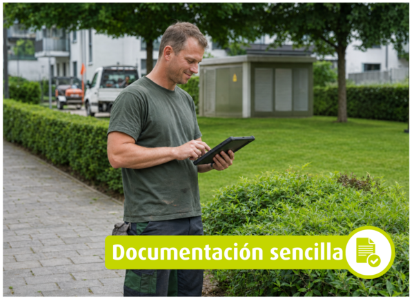 Hombre utilizando una tableta junto a un seto en una zona ajardinada. Texto en la imagen: «Documentación sencilla».